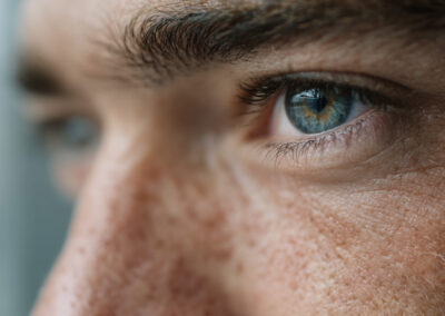 Close-up of a person's blue eye with visible eyelashes and freckled skin surrounding it.