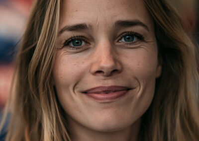 Close-up of a smiling woman with blue eyes and light brown hair, cropped to her face.